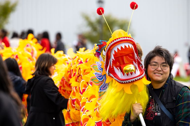 Person carrying a yellow dragon during a parade